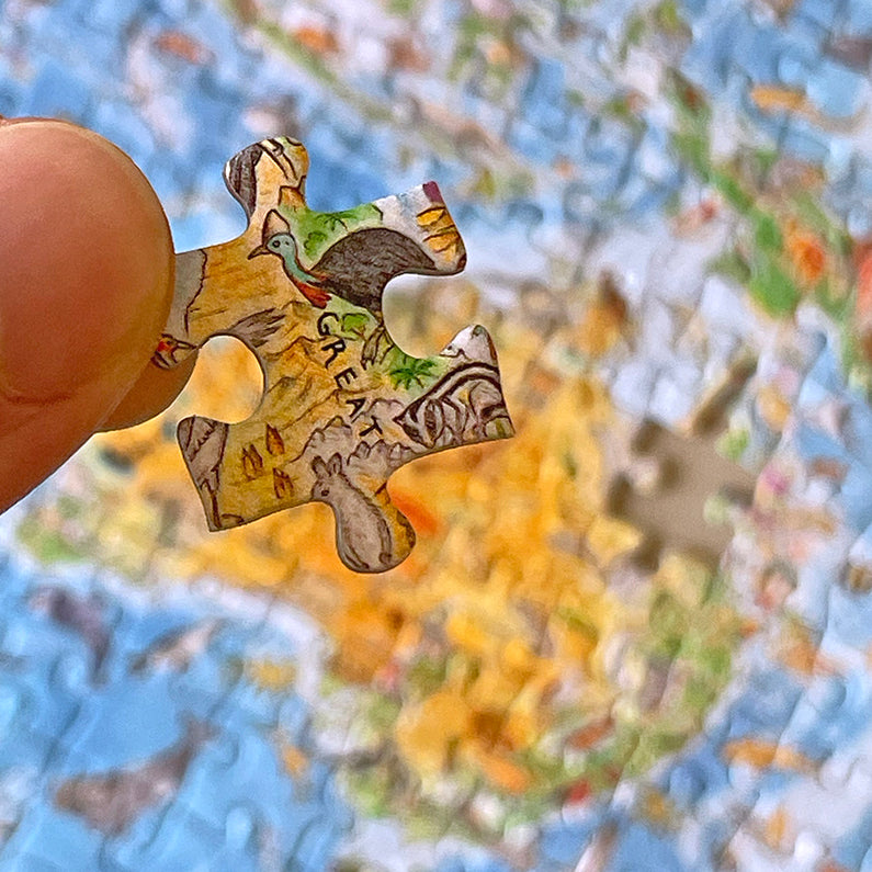 A hand holding a puzzle piece that features an animal with a whole puzzle as background